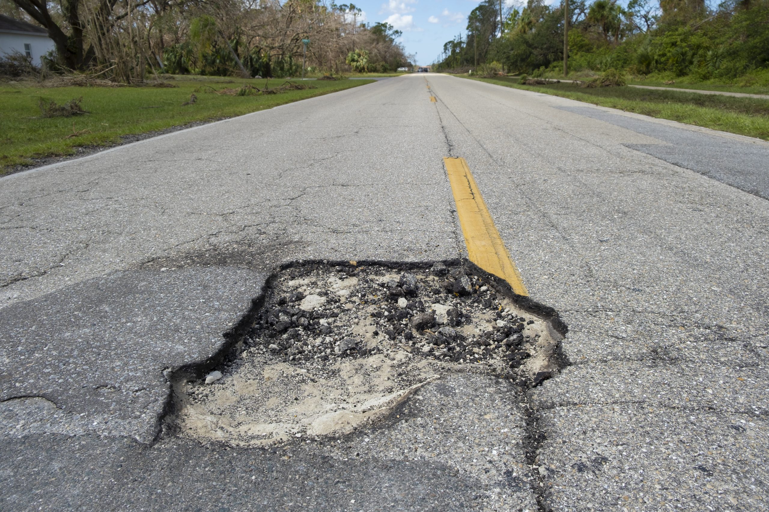 Dangerous pothole on american road surface. Ruined driveway in urgent need of repair.